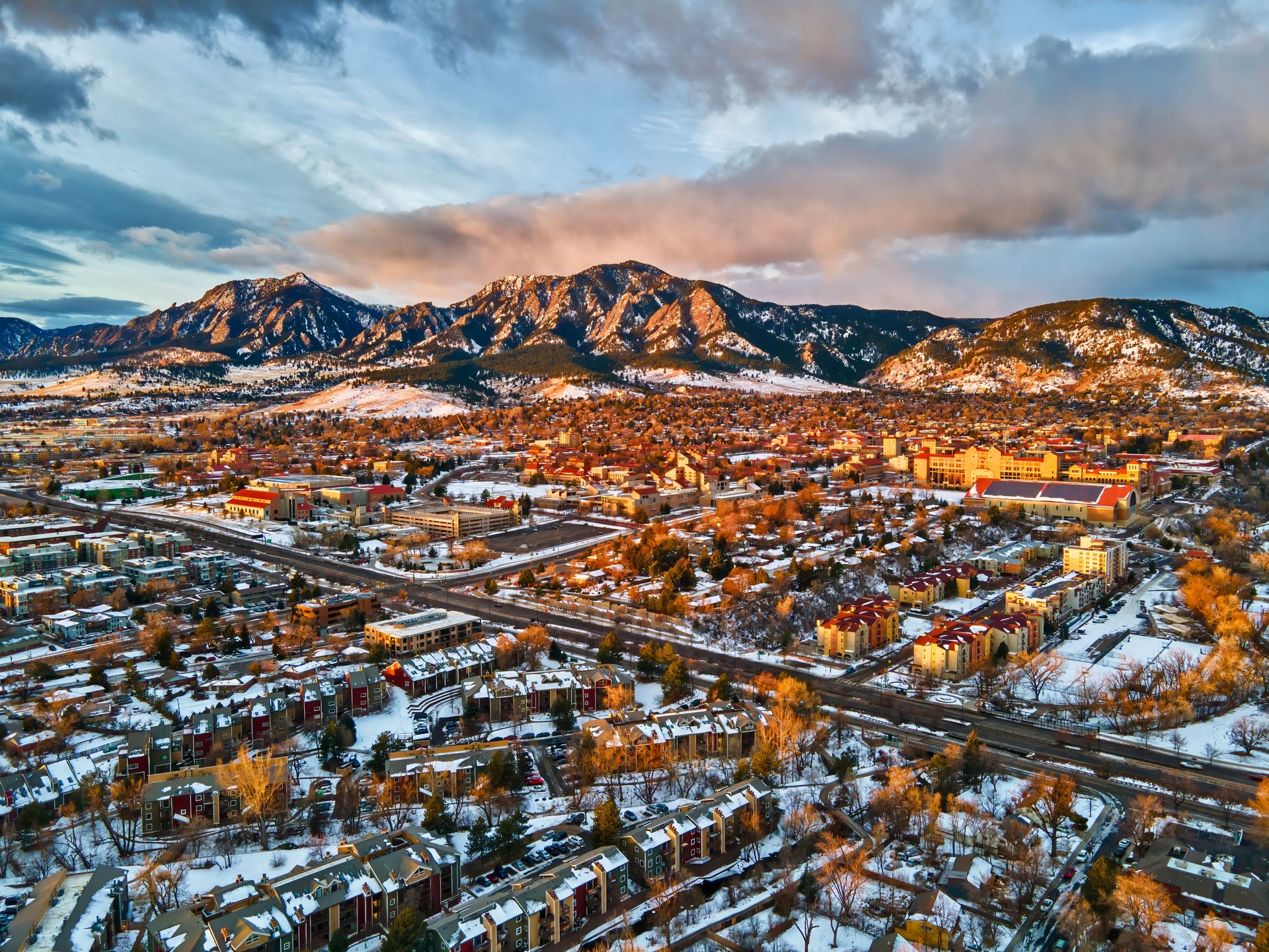 Drone view of University of Colorado, Boulder and the Flatirons at sunrise in the winter snow.